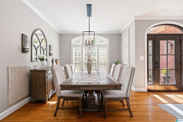 dining room with crown molding, an inviting chandelier, and light hardwood / wood-style floors