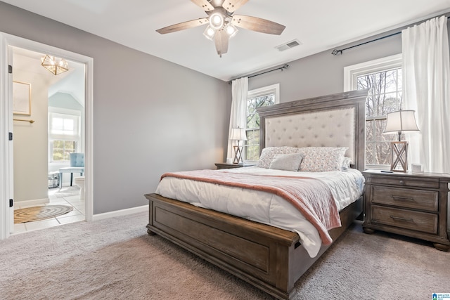 carpeted bedroom with multiple windows, connected bathroom, and ceiling fan with notable chandelier