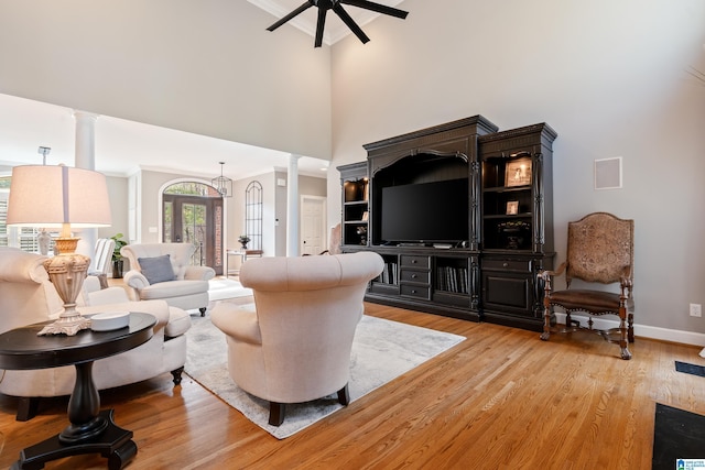 living room featuring ornate columns, wood-type flooring, a high ceiling, and ceiling fan