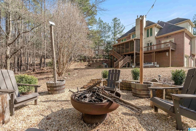 view of yard featuring a deck, a sunroom, and an outdoor fire pit