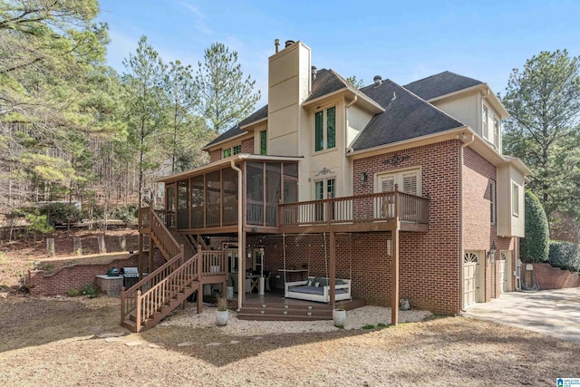 rear view of house with a garage, a sunroom, and a deck