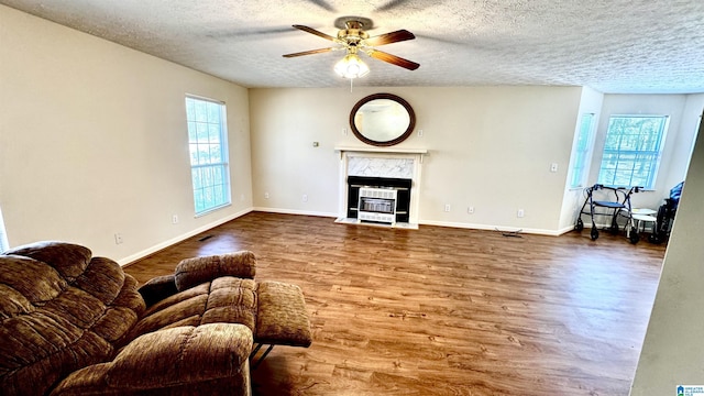 living room with ceiling fan, plenty of natural light, hardwood / wood-style floors, and a fireplace