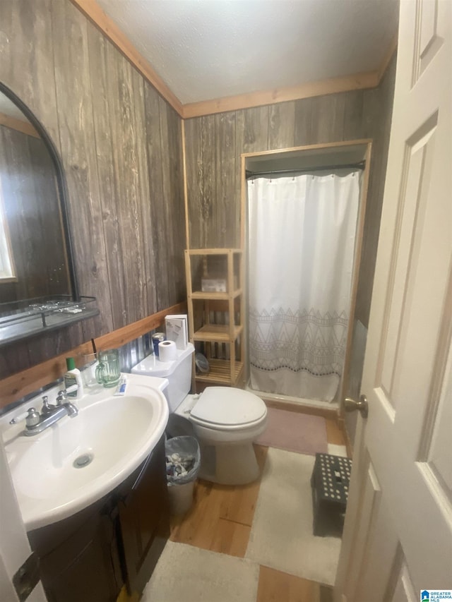 bathroom featuring wooden walls, toilet, a shower with curtain, wood finished floors, and vanity