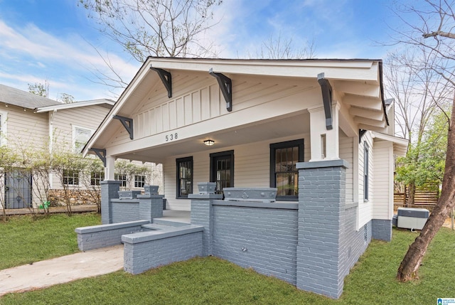 view of front of property with exterior kitchen, a front lawn, board and batten siding, and brick siding