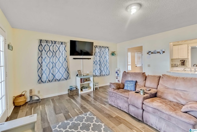 living room featuring sink, hardwood / wood-style floors, and a textured ceiling