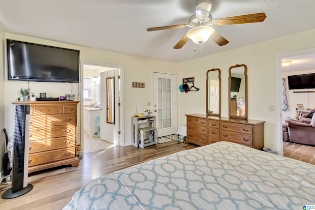 bedroom featuring ceiling fan, connected bathroom, a textured ceiling, and light hardwood / wood-style floors