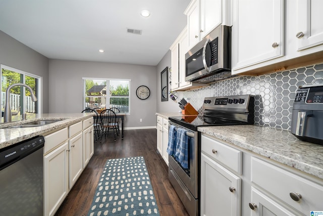 kitchen featuring light stone counters, sink, stainless steel appliances, and white cabinets