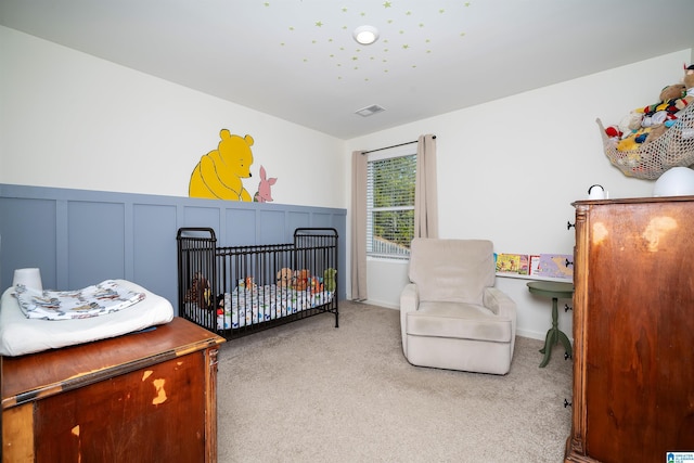 bedroom with a nursery area and carpet flooring