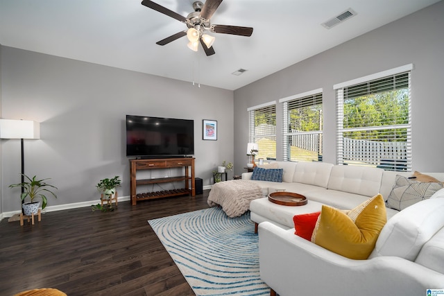 living room with dark hardwood / wood-style flooring, ceiling fan, and a healthy amount of sunlight