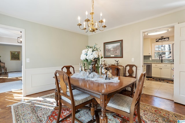 dining room featuring crown molding, sink, light parquet flooring, and an inviting chandelier