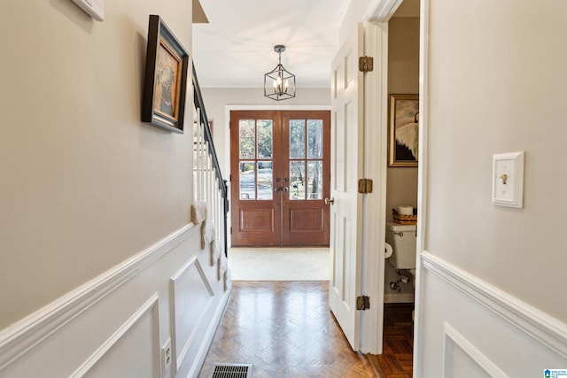 doorway to outside with french doors, parquet flooring, ornamental molding, and a notable chandelier