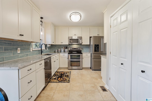 kitchen featuring sink, white cabinetry, stainless steel appliances, light stone countertops, and light tile patterned flooring