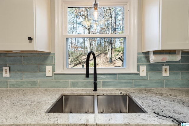 kitchen with white cabinetry, light stone countertops, sink, and backsplash