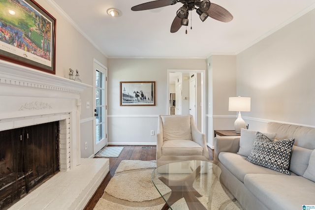 living room with hardwood / wood-style floors, crown molding, a brick fireplace, and ceiling fan