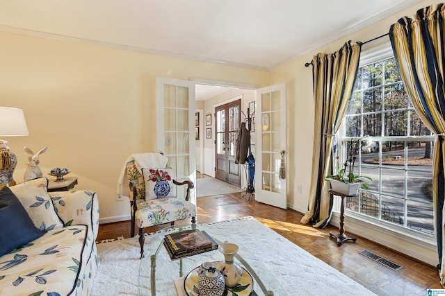 sitting room featuring french doors, crown molding, and light parquet floors