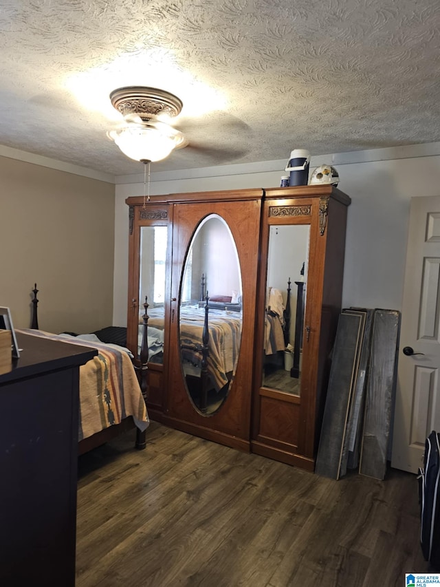 bedroom with dark hardwood / wood-style floors and a textured ceiling