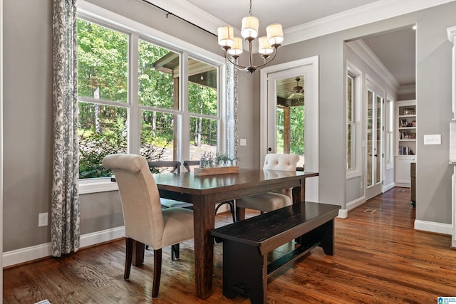 dining room featuring ornamental molding, plenty of natural light, dark wood-type flooring, and an inviting chandelier