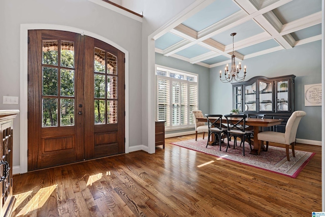 entrance foyer with beamed ceiling, dark hardwood / wood-style flooring, coffered ceiling, an inviting chandelier, and french doors