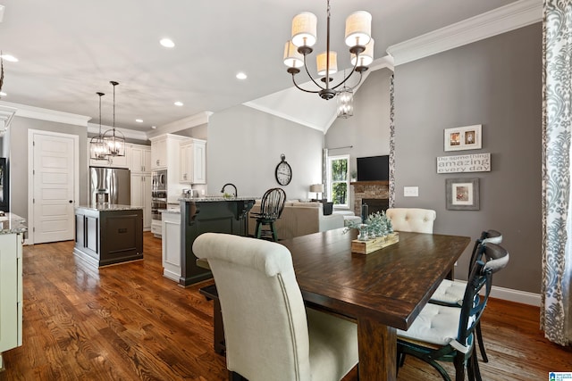 dining area featuring an inviting chandelier, dark wood-type flooring, a fireplace, and ornamental molding