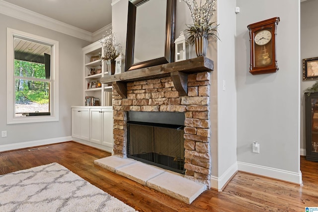 unfurnished living room featuring hardwood / wood-style flooring, ornamental molding, and a stone fireplace