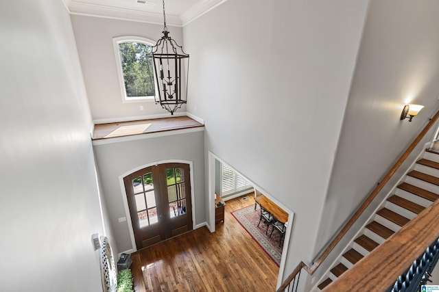 foyer with dark hardwood / wood-style flooring, crown molding, a wealth of natural light, and french doors