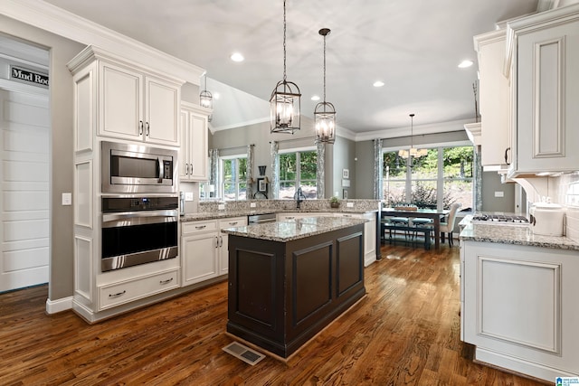 kitchen featuring pendant lighting, stainless steel appliances, a center island, light stone countertops, and white cabinets