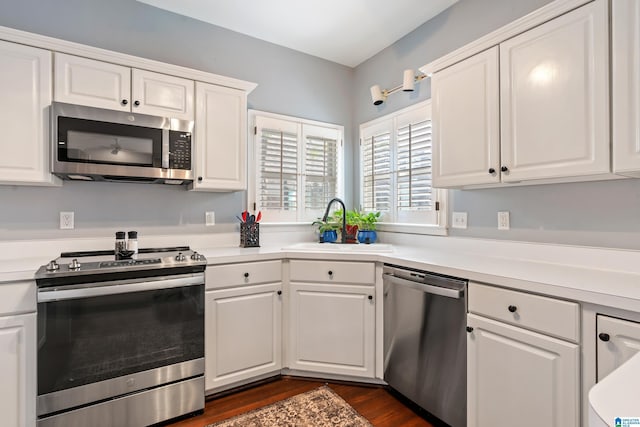 kitchen featuring dark hardwood / wood-style flooring, sink, stainless steel appliances, and white cabinets