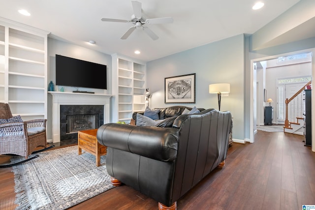 living room with a tiled fireplace, ceiling fan, and dark hardwood / wood-style floors