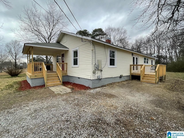 view of home's exterior featuring a chimney, gravel driveway, a deck, and crawl space