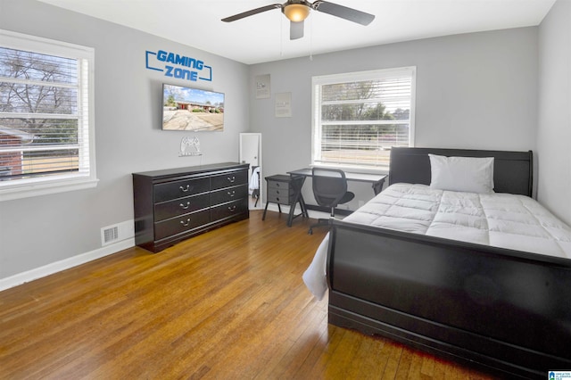 bedroom featuring light hardwood / wood-style floors, ceiling fan, and multiple windows