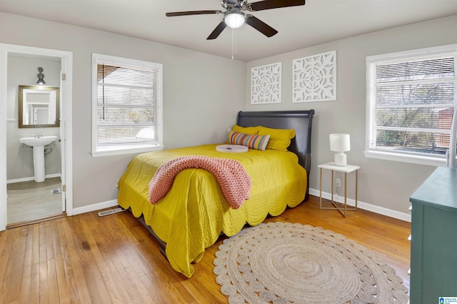 bedroom with ceiling fan, sink, ensuite bathroom, and hardwood / wood-style floors