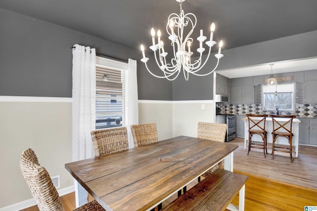 dining room with light wood-type flooring and an inviting chandelier