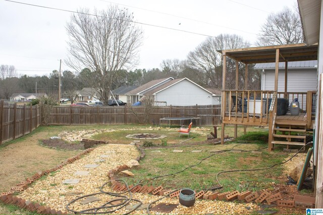 1536 Buckelew Bridge Rd, Anniston, AL 36207 - view of yard featuring an outdoor fire pit, a fenced backyard, a trampoline, and a wooden deck