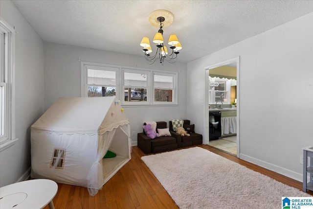 interior space with an inviting chandelier, a textured ceiling, ensuite bath, baseboards, and hardwood / wood-style flooring