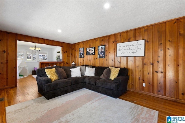 living area featuring hardwood / wood-style flooring, a textured ceiling, and a notable chandelier