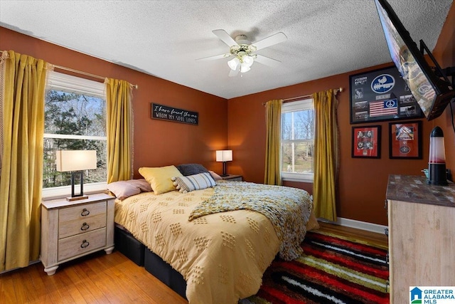 bedroom featuring a textured ceiling, ceiling fan, light wood-type flooring, and baseboards