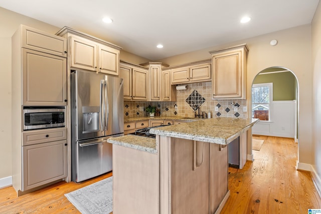 kitchen featuring appliances with stainless steel finishes, a breakfast bar, light stone counters, a center island, and light wood-type flooring