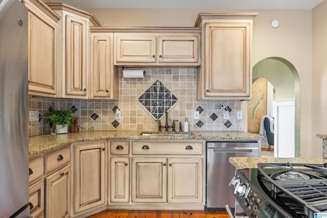 kitchen featuring stainless steel appliances, sink, light stone counters, and light brown cabinets