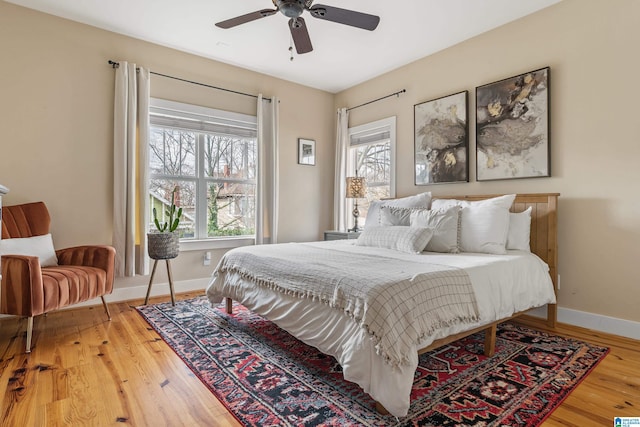 bedroom with multiple windows, wood-type flooring, and ceiling fan