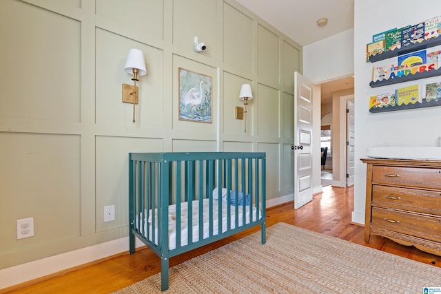 bedroom with light wood-type flooring and a crib