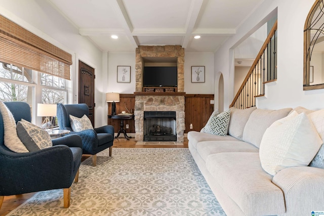 living room with coffered ceiling, beamed ceiling, a fireplace, and light hardwood / wood-style floors