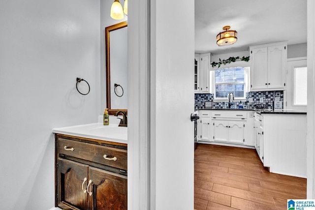 kitchen featuring light hardwood / wood-style floors, white cabinetry, sink, and tasteful backsplash