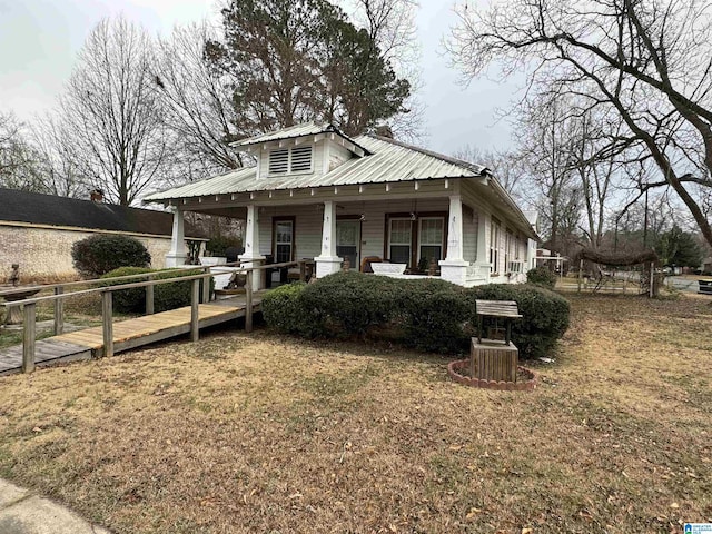 view of front of home with a porch, a front yard, and metal roof