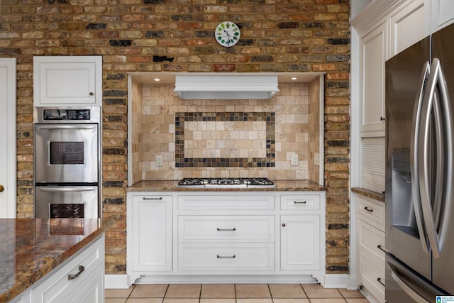 kitchen with appliances with stainless steel finishes, dark stone counters, and white cabinetry