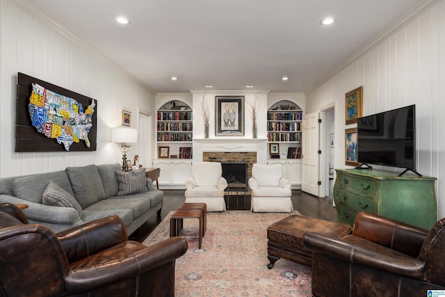 living area featuring ornamental molding, a brick fireplace, wood finished floors, and built in features