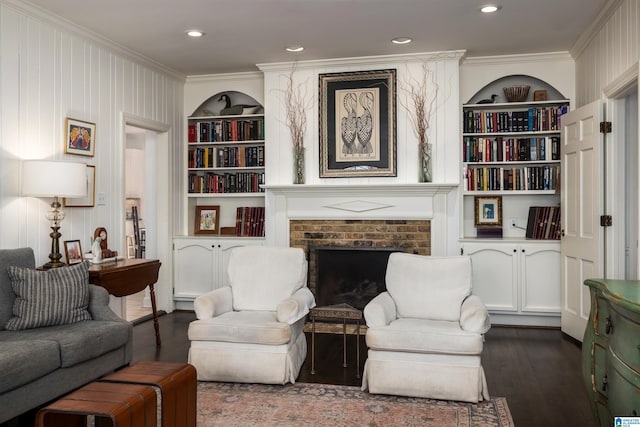 living area featuring ornamental molding, a fireplace, built in shelves, and dark wood-style floors