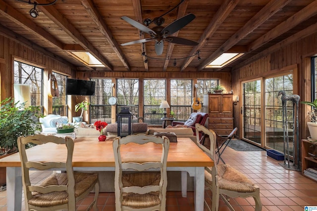 dining area with beamed ceiling, wood walls, a skylight, and a wealth of natural light