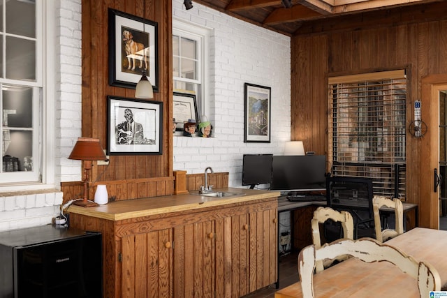 interior space with brick wall, a sink, beam ceiling, and wooden walls