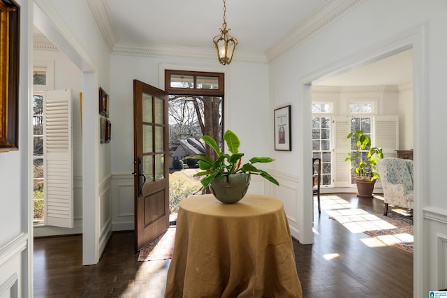 entrance foyer with a decorative wall, wainscoting, parquet flooring, and crown molding