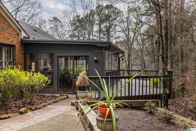 view of exterior entry featuring brick siding and a deck